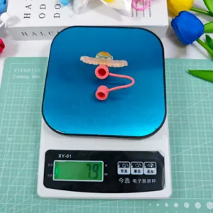 Detailed shot of cute acrylic straw cover accessory, showing its lightweight design on scale.