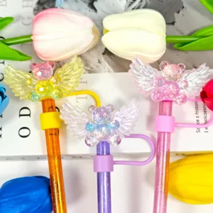 Close-up of cute glitter bear wing straw covers and plugs, colorful drink accessories.