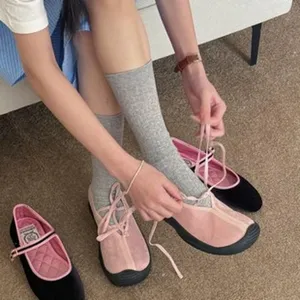 Close-up detail view of stylish ribbon lace-up flat shoes paired with cozy grey mid-calf socks.