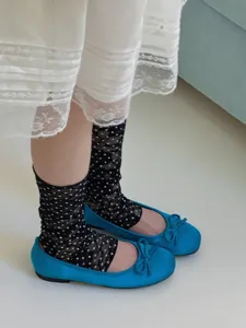 Vue détaillée de chaussettes en dentelle noire à pois assorties à des chaussures plates.