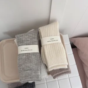 Detailed shot of thick wool socks in cozy neutral shades, featuring soft ribbed knit texture.