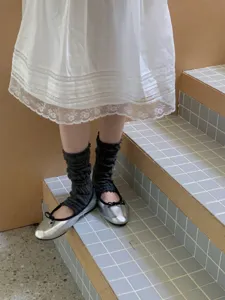 Gedetailleerd overzicht van donkergrijze, geplooide stijgbeugel-beenwarmers en ballerina's.