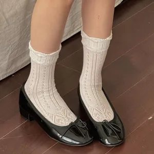 Close-up detail shot of women's white lace mesh crew socks paired with classic black shoes.
