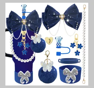 Dark blue tumbler accessories set including silicone boot, bow, pearl chain, and pom-pom keychain.