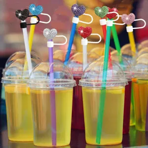 Gros plan détaillé de couvercles de paille en forme de cœur en strass étincelants sur des tasses.