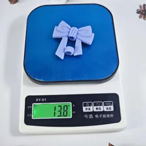 Silicone bow straw cover detail view, showing product weight and size on scale clearly.