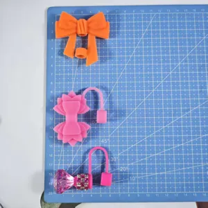 Silicone straw topper detail showing bow and diamond dust plug accessories for tumblers.