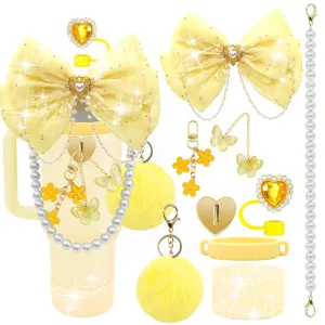 Vista dettagliata degli accessori per tazza Stanley gialla con fiocco, catena di perle e ponpon.