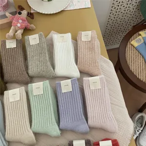 Detail view of thick knit solid color mid-calf socks in various cozy winter shades.