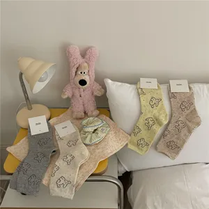 Cozy dog patterned mid tube cotton socks displayed in warm bedroom scene detail view.