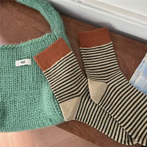 Detail shot of striped mid-calf socks with contrast color cuffs, cozy knit casual style for autumn.