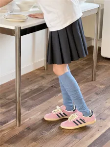 Chaussettes bleu clair associées à des baskets roses et jupe plissée, photo de détail.