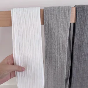 Detailed view of solid color ribbed cable knit tights in white, light and dark grey tones.