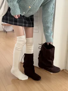 Detailed shot showcasing soft knit over-the-knee socks and stylish slouchy boots outfit.