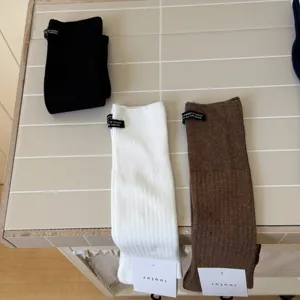 Detailed view of IOULOR casual solid color cotton calf socks in black white and brown.