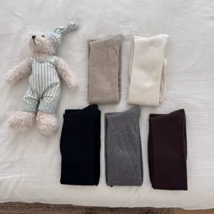 Detail view of cozy knit over-knee socks in solid colors with a cute plush bear prop.