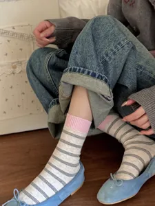 Close-up detail shot of Japanese style striped mid-tube socks with pink cuffs on foot.