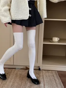 Detailed shot of white cable knit over the knee socks, soft fabric, preppy cute style.