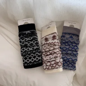 Detailed shot of cozy knit Fair Isle leg warmers with branded cards, soft winter warm accessory.