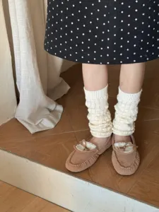Detailed shot of white cable knit leg warmers showing textured winter warm slouch socks design.
