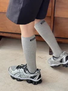Close-up detail of gray knit calf socks with stylish woven label, soft breathable texture.
