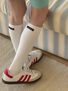 White calf socks with stylish black text label, comfortable cotton casual knit design detail.