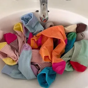 Dettaglio di calze slouch a costine colorate impilate, morbida struttura in cotone pettinato.