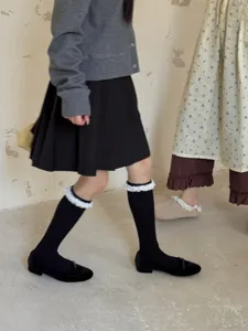 Vue détaillée de charmantes chaussettes noires douces avec bordure en dentelle blanche.