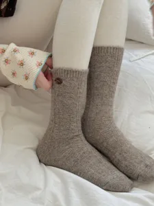 Cozy knit wool mid-calf socks with delicate wooden button detail, warm autumn winter wear.