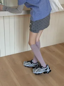 Detail shot of solid color knee-high calf socks in light purple, soft knit fabric on model.