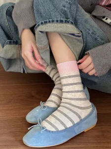 Detail view of stylish striped mid-calf socks with pink ribbed cuffs, paired with shoes.