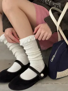 Gros plan détaillé de chaussettes slouch blanches pour femmes à volants et rayures douces.