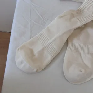 Close-up detail of women solid color knit slouch socks in soft beige cotton fabric.