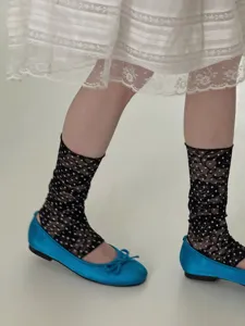 Vue détaillée de chaussettes en dentelle noire à pois transparentes avec chaussures plates.