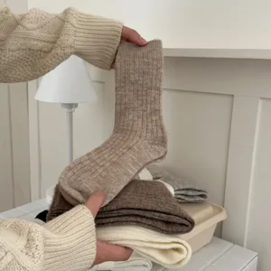 Detail view of thick winter warm knit mid-calf socks in solid oatmeal color, cozy texture.