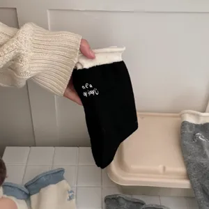 Vista dettagliata delle calze a polso in maglia a contrasto con eleganti ricami.