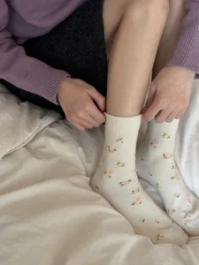Detail shot of vintage floral crew socks on white bedding, showcasing soft knit texture.