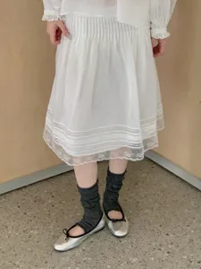 Detailopname van donkergrijze gerimpelde stijgbeugelsokken gecombineerd met zilveren ballerina's.