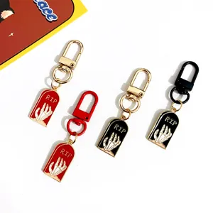 Close-up details of Halloween tombstone skeleton hand metal keychains in multiple colors.
