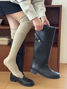 Detail shot of beige wool over-the-knee socks worn with boots, soft texture and cozy warmth.