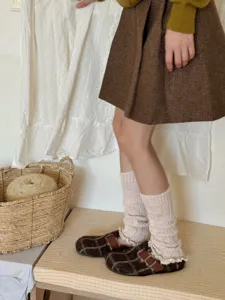 Detailed shot of cream ruffled leg warmers, chunky knit winter y2k aesthetic boot cuffs.