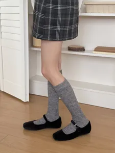 Detail view of Japanese minimalist grey ribbed calf socks paired with casual shoes and skirt.
