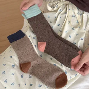 Close-up of cozy merino wool mid-tube socks with contrast color cuffs and heels, soft knit texture.