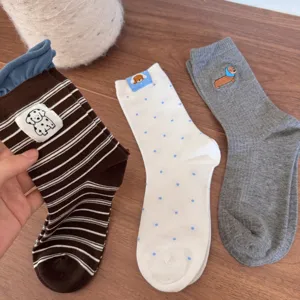 Close-up of cute cartoon embroidered dachshund and puppy socks with soft cotton fabric.