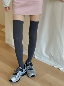 Detail shot of dark grey cable knit over the knee socks styled with sneakers for daily wear.