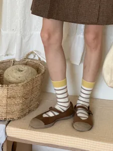 Detailed shot of Japanese style striped mid-calf socks featuring contrasting yellow cuffs.