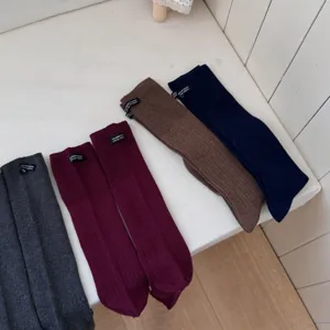 Detailed view of solid color long socks in multiple shades like grey, brown, and navy blue.