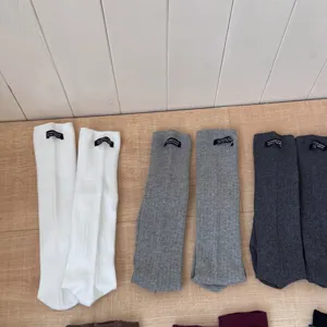 Detail view of Korean style solid color ribbed cotton tube socks with letter labels.