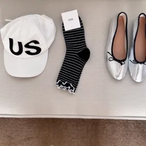 Detail shot featuring a stylish matching set with a white cap, striped socks, and silver flats.