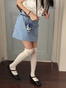 Detail shot of white scrunch over-the-knee socks paired with a blue plaid skirt and shoes.